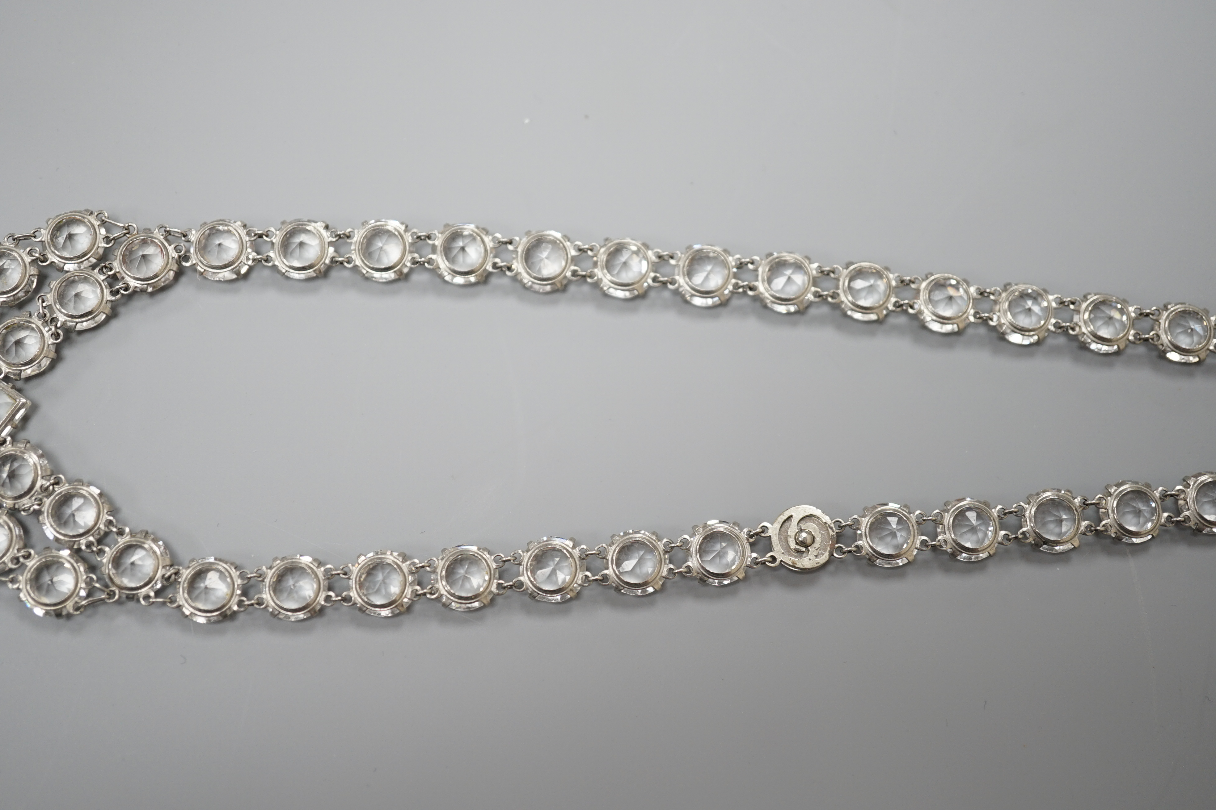 An early 20th century ornate white metal and facet cut paste set drop necklace, overall approx. 44cm.